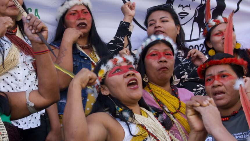 A group of women with headdresses and red face paint shout together