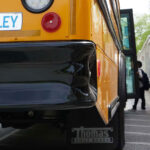 an electric school bus with children lining up to board it