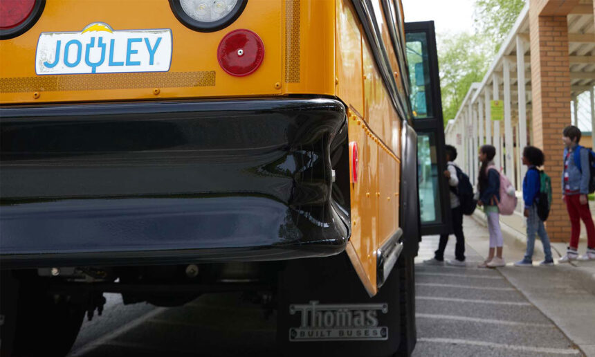 an electric school bus with children lining up to board it