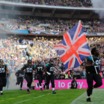 NFL players running onto a field with union jack flag