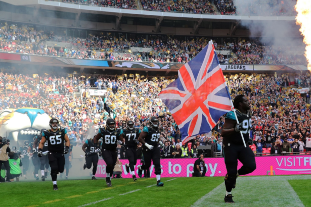 NFL players running onto a field with union jack flag