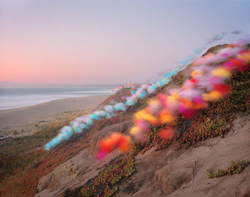 tufts of colorful tulle float down a hill by a beach