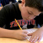 Picture of a boy filling out a We Have Choices daily tracker to monitor his self-regulation skills