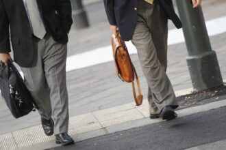 White men in suits carrying briefcases cross a street.