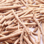 A pile of light brown roots of the ashwagandha plant on a white background