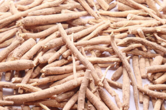 A pile of light brown roots of the ashwagandha plant on a white background