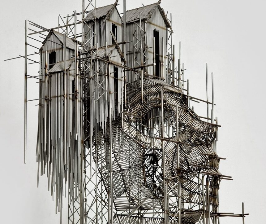 a wall sculpture made of numerous pieces of steel wire assembled in an abstract composition of house-like forms on scaffolding and the outline of a face