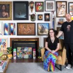 a portrait of gallerists Shawn and Andrew Hosner in their home, standing in front of a wall of paintings and artworks