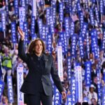 US Vice President and 2024 Democratic presidential candidate Kamala Harris waves on stage with a crowd of supporters holding "Kamala" signs in the background as she arrives to speak at the Democratic National Convention in Chicago, Illinois, on August 22, 2024