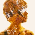 a double exposure photo of a child's silhouette filled with branches and orange leaves