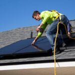 A man installing a solar panel on a rooftop.