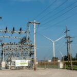 An electrical station with a wind turbine next to it