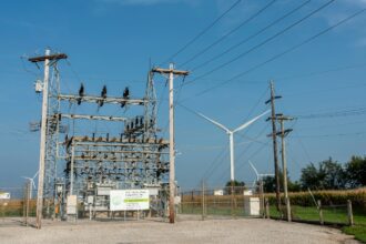 An electrical station with a wind turbine next to it