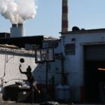 A young person plays basketball behind a truck stop restaurant as emissions spew out of a large stack nearby at the coal-fired Morgantown Generating Station on the Potomac River in Newburg, Maryland.