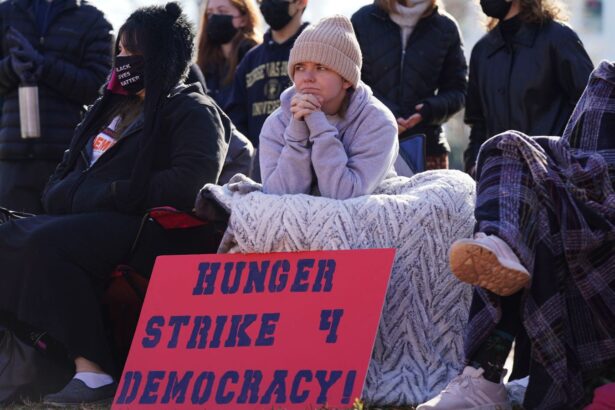 A coalition of conservative, progressive, and independent students, some over eight days into a hunger strike, congregate in front of the White House to urge President Biden to prioritize voting rights at Lafayette Park in December 2021 in Washington, DC. Centered is a young person holding a sign that reads Hunger Strike 4 Democracy!