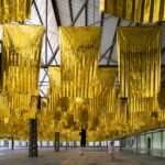 an installation of hundreds of metallic rescue blankets suspended from the ceiling of an old factory