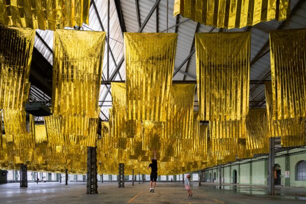 an installation of hundreds of metallic rescue blankets suspended from the ceiling of an old factory