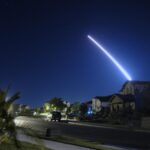 photo of a Minuteman missile launched from Vandenberg Air Force Base in California streaking across the night sky over a suburban neighborhood