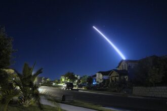 photo of a Minuteman missile launched from Vandenberg Air Force Base in California streaking across the night sky over a suburban neighborhood