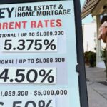 Pedestrians walk by a sidewalk sandwich board providing the latest interest rates for home mortgages.