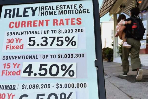 Pedestrians walk by a sidewalk sandwich board providing the latest interest rates for home mortgages.