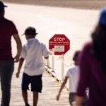 Visitors walk past a sign reading "Stop Extreme Heat Danger"