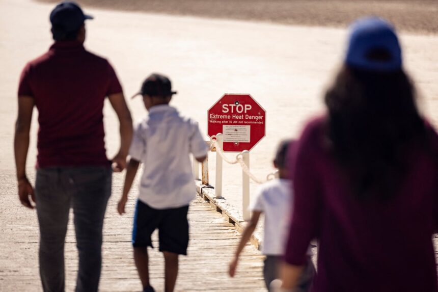 Visitors walk past a sign reading "Stop Extreme Heat Danger"