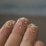 Closeup of fingers with microplastics on their tips.