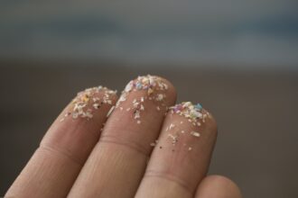 Closeup of fingers with microplastics on their tips.