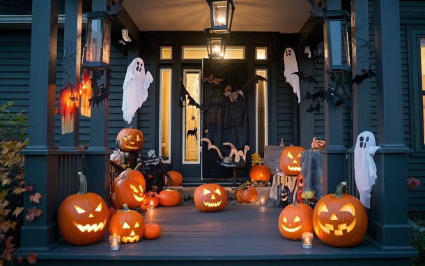 A porch decorated with ghosts and pumpkins for Halloween.