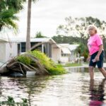 A woman walks along a flooded street in the aftermath of Hurricane Milton on October 10, 2024 in Osprey, Florida.