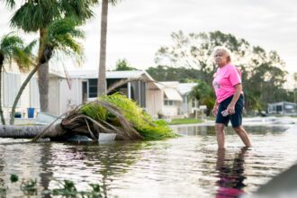 A woman walks along a flooded street in the aftermath of Hurricane Milton on October 10, 2024 in Osprey, Florida.