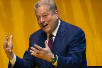 Photo of Al Gore talking with passion in front of an orange background