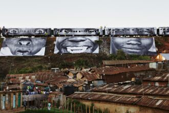 a procession of train cars above a village depicts 3 large black and white photographs of expressive faces