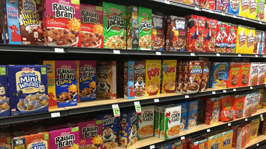 Grocery store shelves, filled with colorful cereals, like Raisin Bran, Apple Jacks, Pops, and Froot Loops.