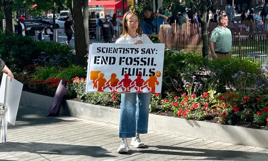 Scientist holding a sign saying "Scientists Say: End Fossil Fuels"