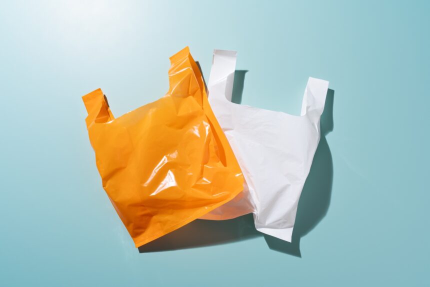 Two plastic bags, one orange and one white, lie flat against a blue background.