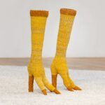 a pair of yellow woven straw boots shaped like bird legs