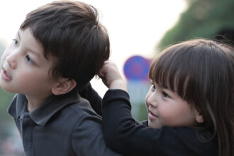 A young child pulls the hair of another child.