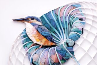 a quilled paper sculpture of a kingfisher in a leaf