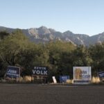 political signs line a highway near a high, dry mountain range