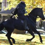 a rider in a headless horseman costume rides by yellow fall leaves