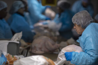 photo of women wearing blue protective gear on either side of the production line in a dimly lit turkey processing plant