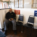 Carlos H. Velilla, a Puerto Rican, sits near signs that say