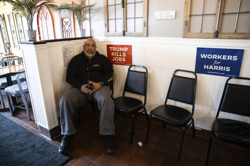 Carlos H. Velilla, a Puerto Rican, sits near signs that say