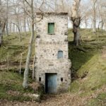 a photograph of a solitary, three-story, stone house in the Italian countryside