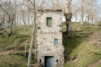 a photograph of a solitary, three-story, stone house in the Italian countryside