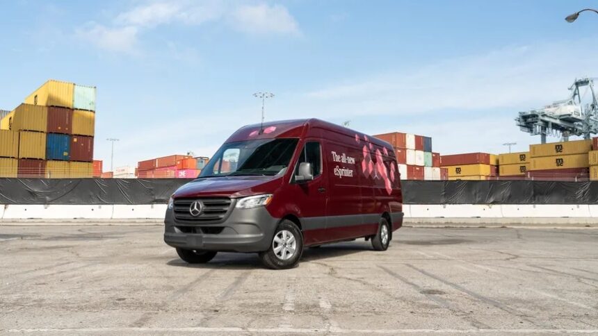 A maroon van sits in an empty lot in front of shipping containers