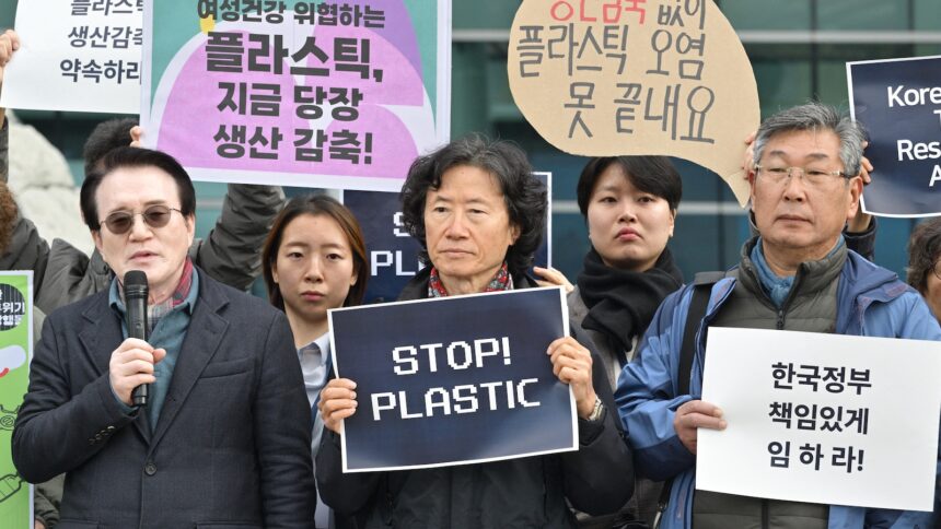 A small group of protesters hold signs, mostly in Korean, but one reads