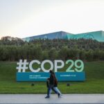 Citizens walks near a sign for COP29 near the Baku Olympic Stadium, the venue of the COP29 United Nations Climate Change Conference on October 23, 2024 in Baku, Azerbaijan.